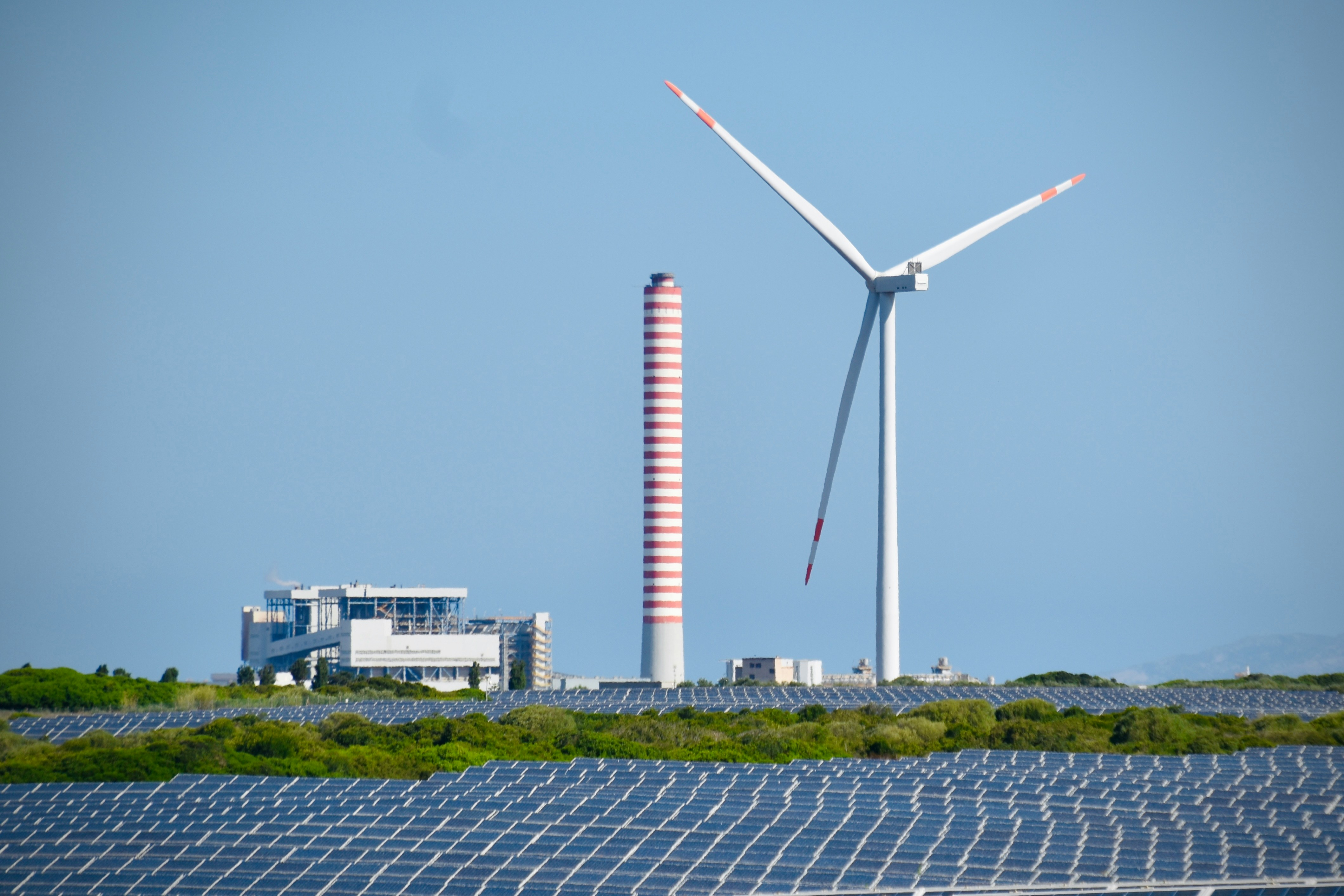 Solar array with a wind turbine and power station on the horizon